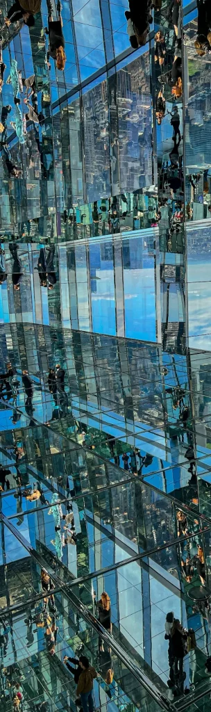 View of Summit One Vanderbilt with glass reflecting the surroundings and indistinct people inside.