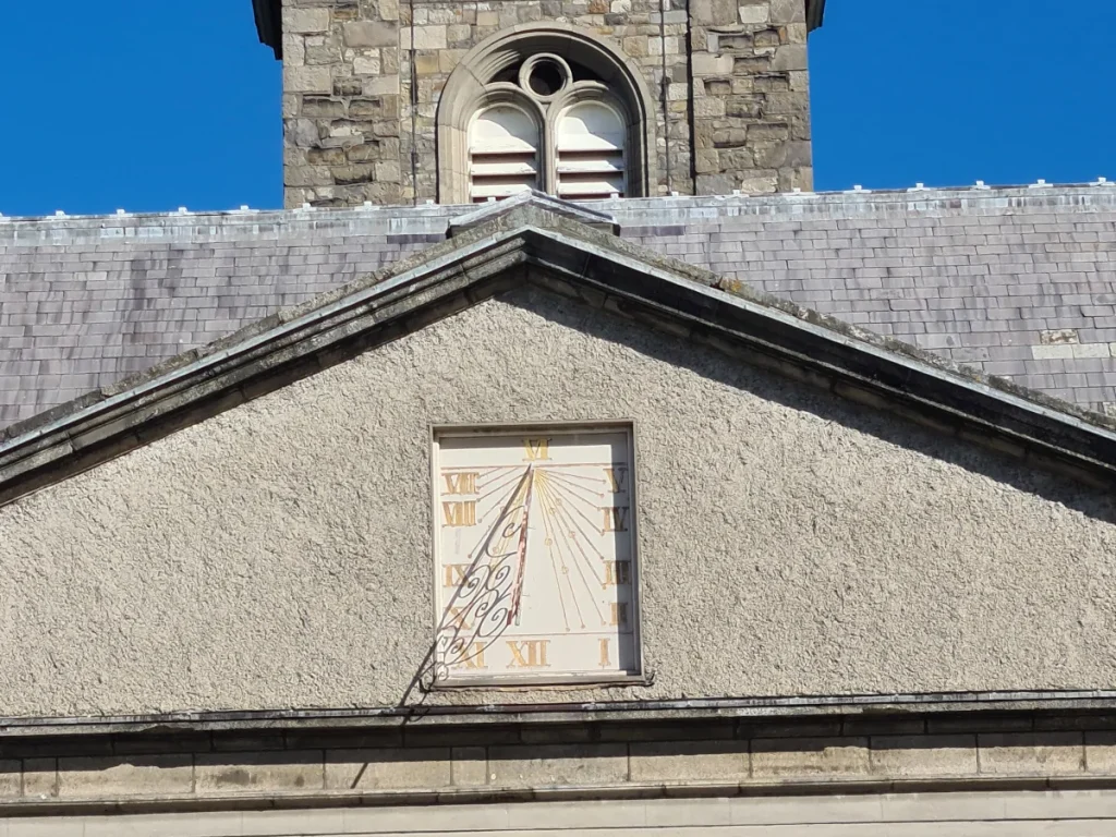 Solar dial on the facade of the Irish Museum of Modern Art in Dublin, featuring wrought iron structure and Roman numerals.