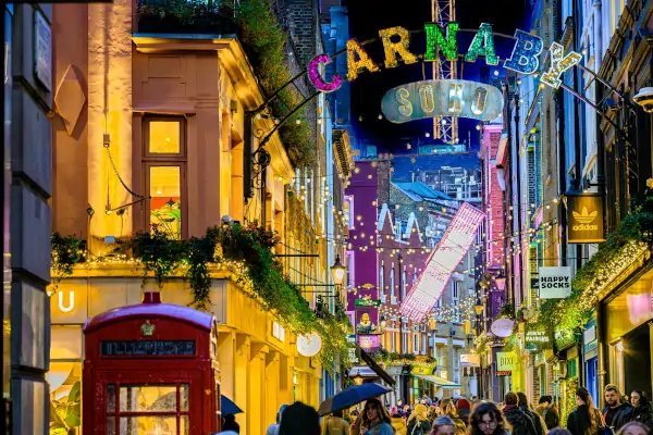 Carnaby Street de noche con luces decorativas, tiendas y ambiente animado en Soho Londres