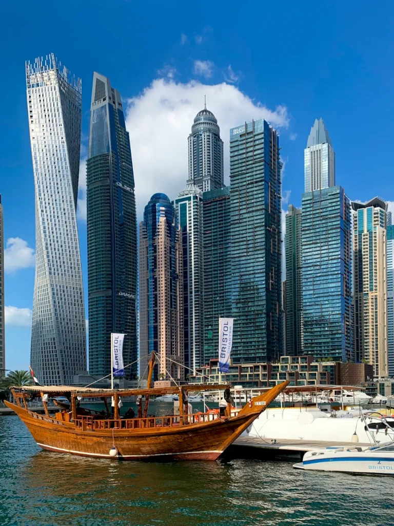 Skyline de Dubai Marina con la icónica Cayan Tower y dhow tradicional en primer plano