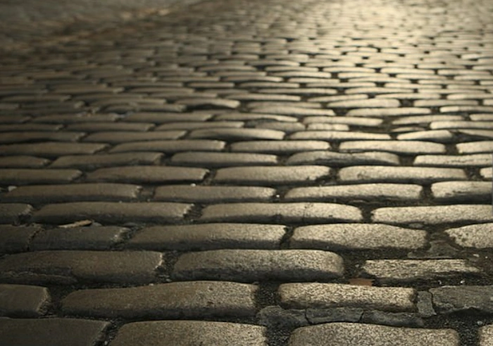 Historic cobblestone streets of Dumbo, Brooklyn, with red-brick buildings and Manhattan Bridge in the background