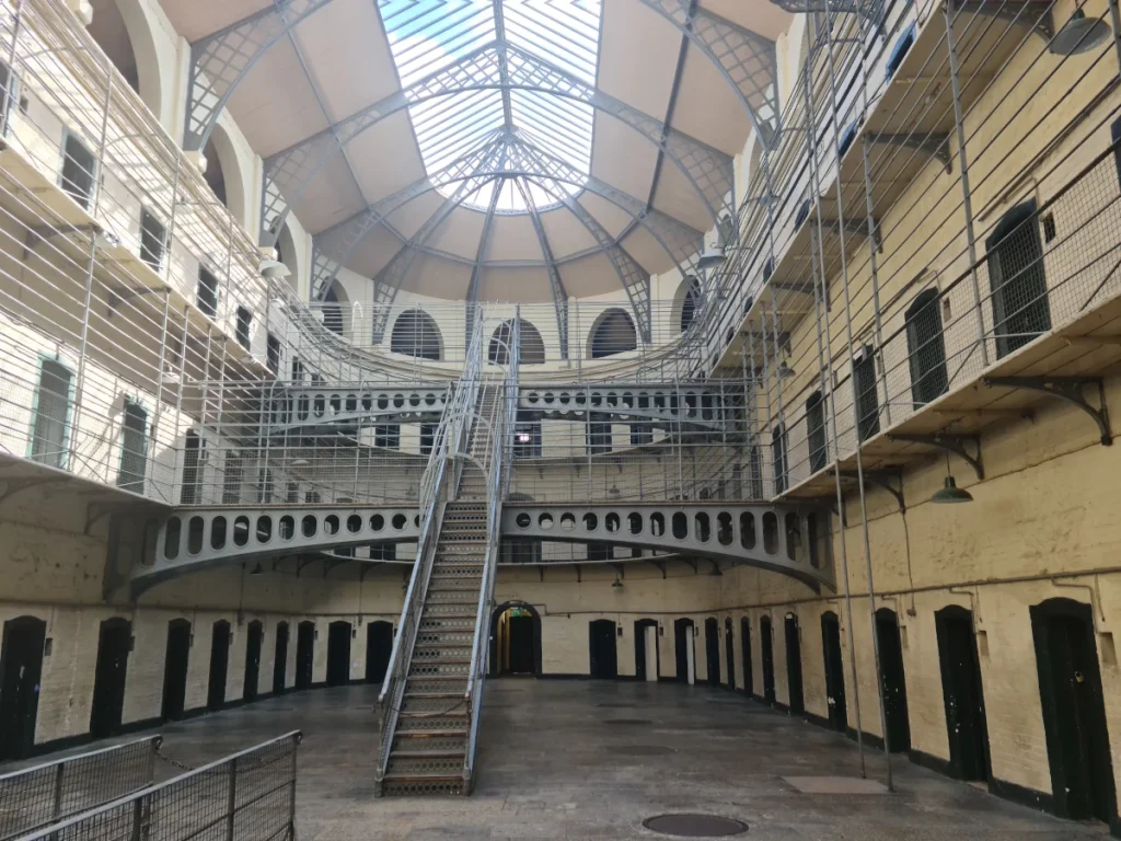 Interior of Kilmainham Gaol prison in Dublin, showing corridor, metal stairs, and cell doors