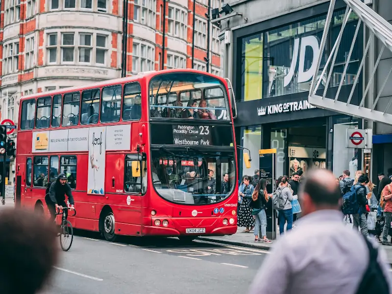 Autobús rojo de dos pisos en Oxford Street con peatones y tiendas en Londres