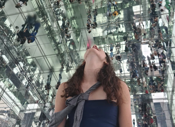 Joven mirando hacia arriba dentro del Summit One Vanderbilt, rodeada de espejos en Nueva York.